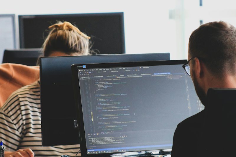 Duas pessoas programando em monitores num escritório
